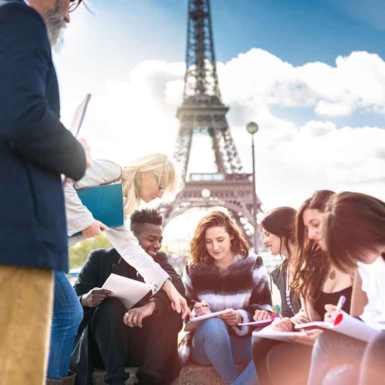 Class studying outdoors in front of the Eiffel tower