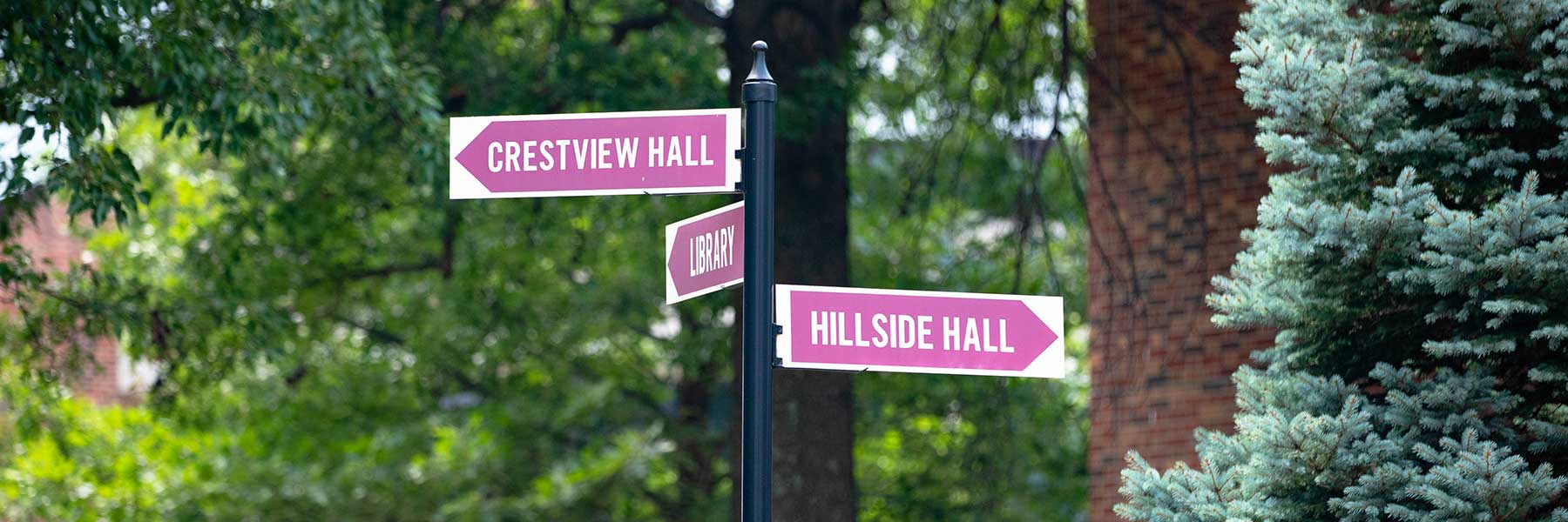Three IU Southeast directional signs on a pole reading Crestview Hall, Library, and Hillside Hall