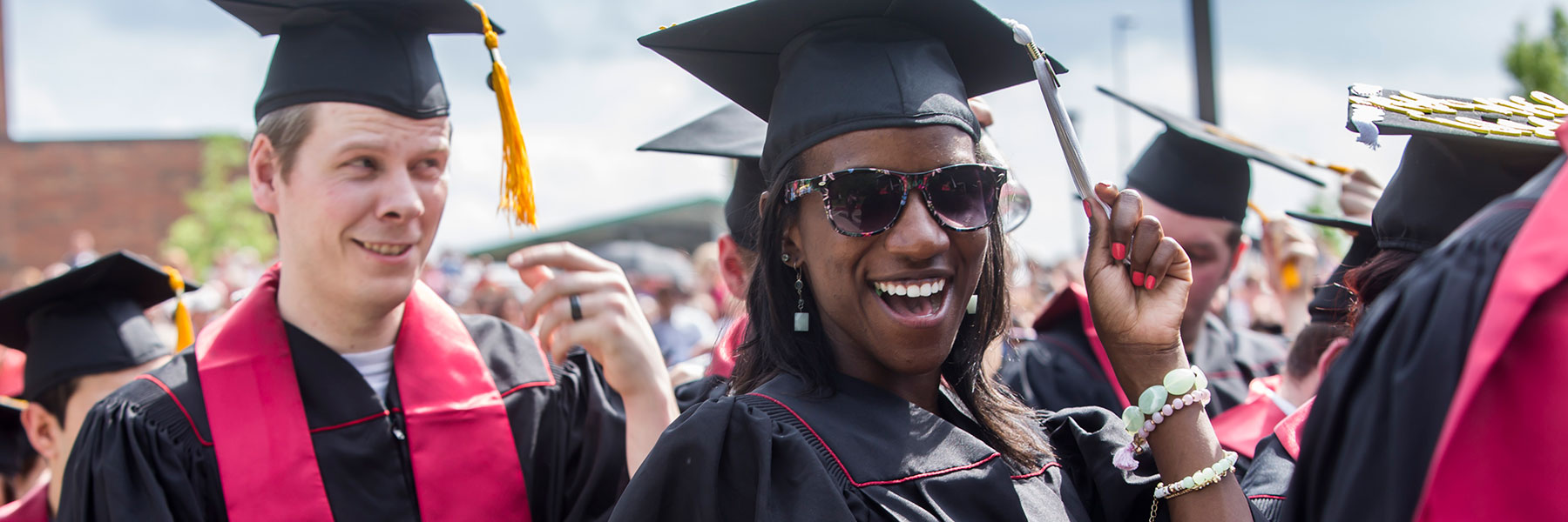 A woman in sunglasses turns her tassel while laughing