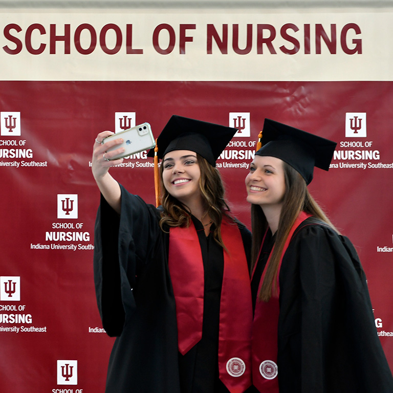 Two young women in graduation attire take a selfie together