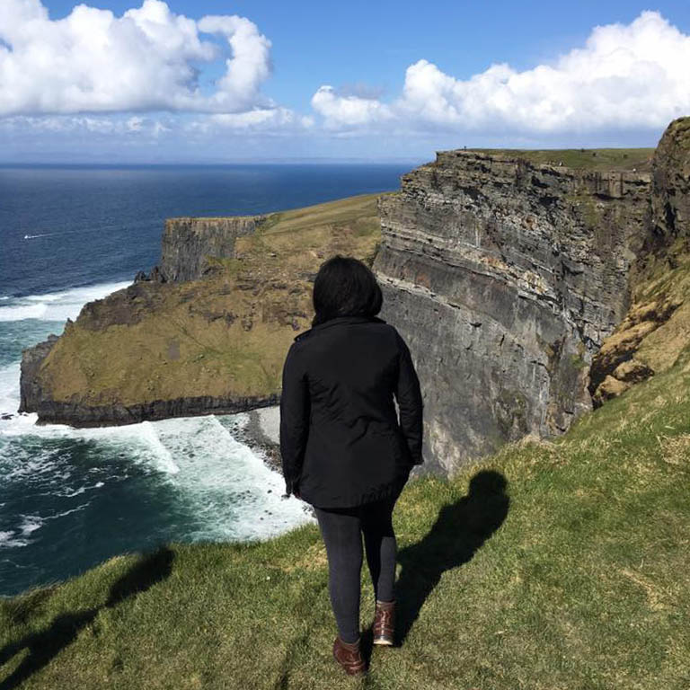 Female student gazing over the cliffs of Ireland